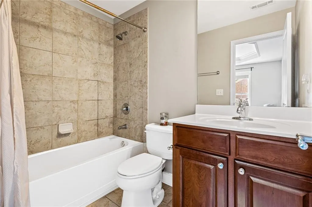 Bathroom featuring shower / bath combination with curtain, vanity, and tile patterned flooring