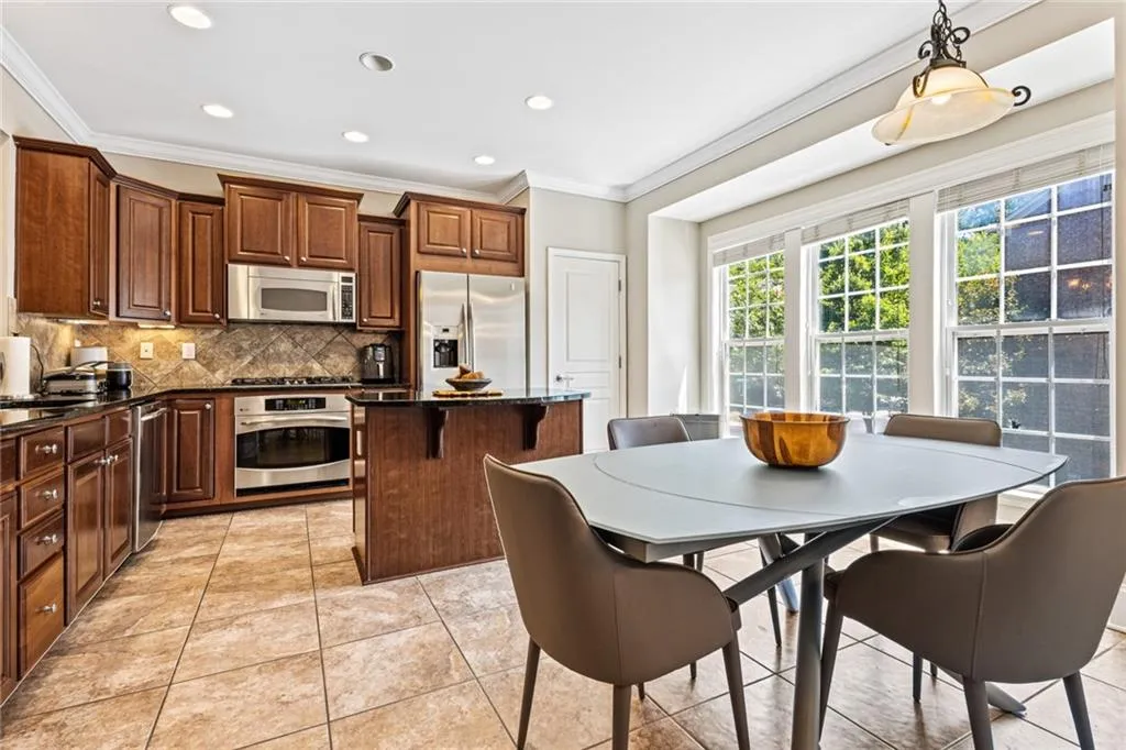 Kitchen with stainless steel appliances, a kitchen island, ornamental molding, decorative backsplash, and recessed lighting