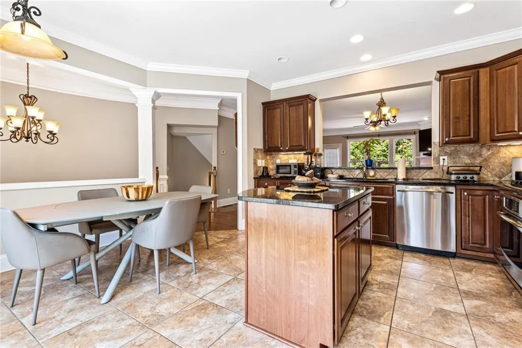 Kitchen featuring a chandelier, backsplash, ornamental molding, dishwasher, and a kitchen island