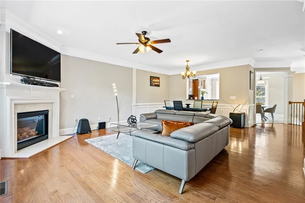 Living area with a ceiling fan, crown molding, a chandelier, a fireplace, and hardwood / wood-style flooring