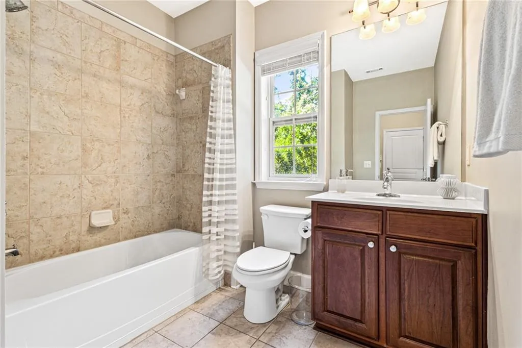 Full bath featuring vanity, shower / bathtub combination with curtain, and tile patterned flooring