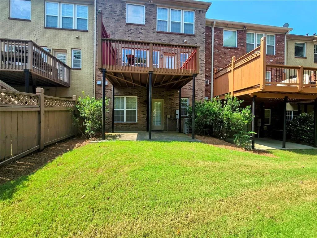 Rear view of house featuring brick siding, a wooden deck, and a patio area