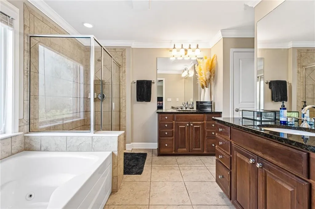 Full bath featuring crown molding, a jetted tub, a stall shower, vanity, and tile patterned flooring