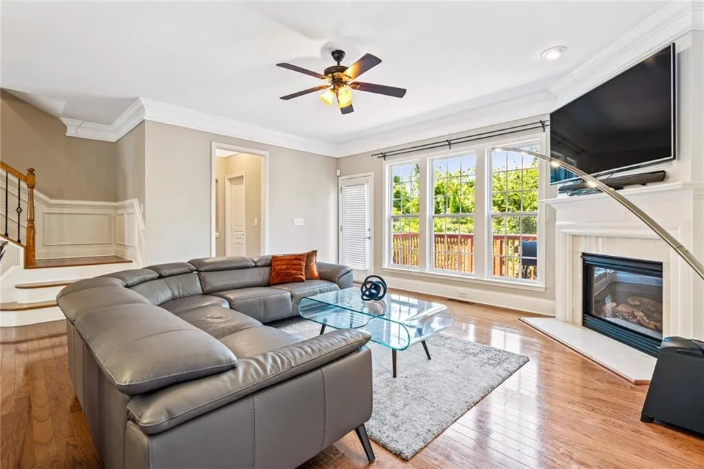 Living room with ornamental molding, wood-type flooring, a ceiling fan, stairway, and a high end fireplace