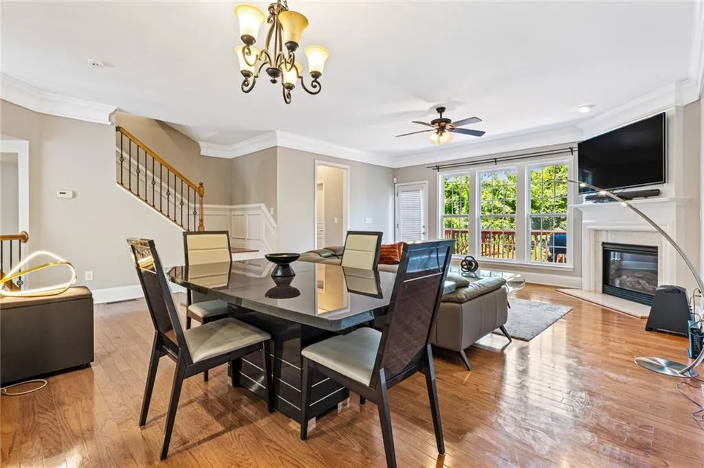 Dining space with crown molding, stairs, light wood-style floors, a premium fireplace, and a ceiling fan