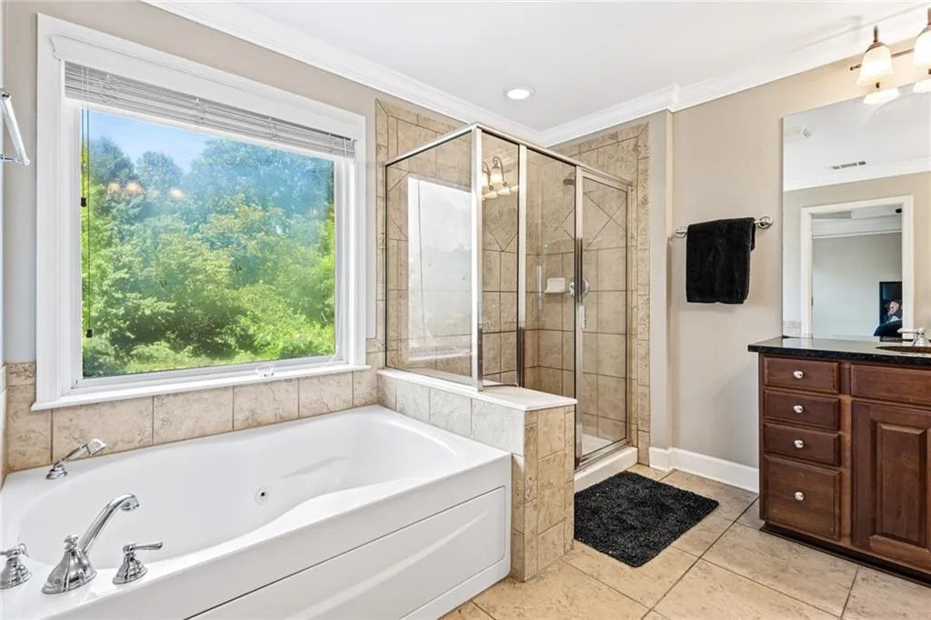 Bathroom with crown molding, a jetted tub, a shower stall, vanity, and tile patterned floors