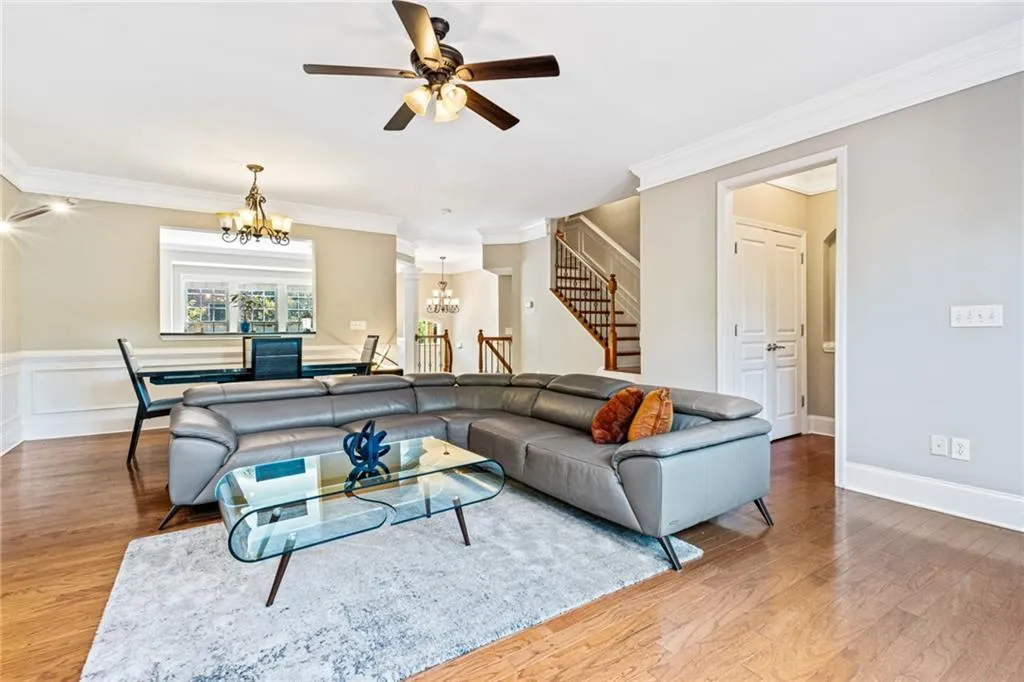 Living area featuring a chandelier, ornamental molding, stairway, ceiling fan, and wood finished floors