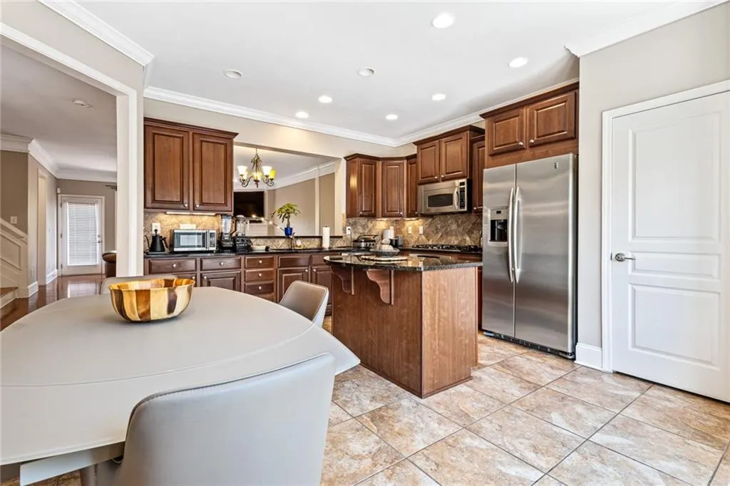 Kitchen featuring decorative backsplash, stainless steel appliances, a chandelier, crown molding, and a kitchen island