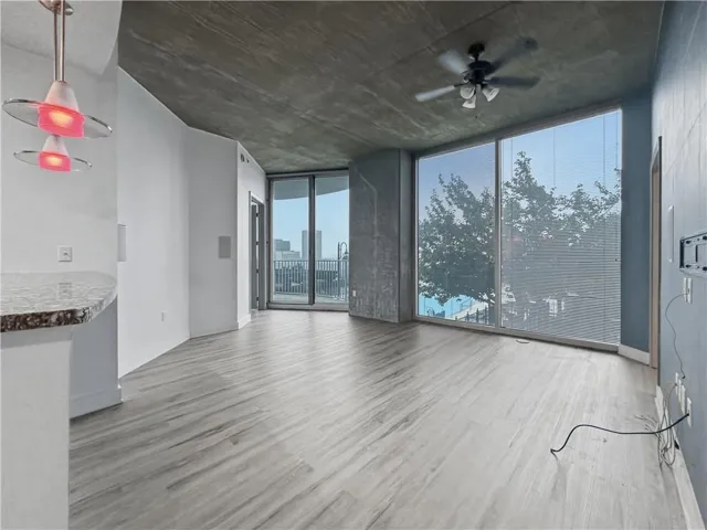 Expansive room featuring large floor-to-ceiling windows, wood-finish flooring, and a textured concrete ceiling