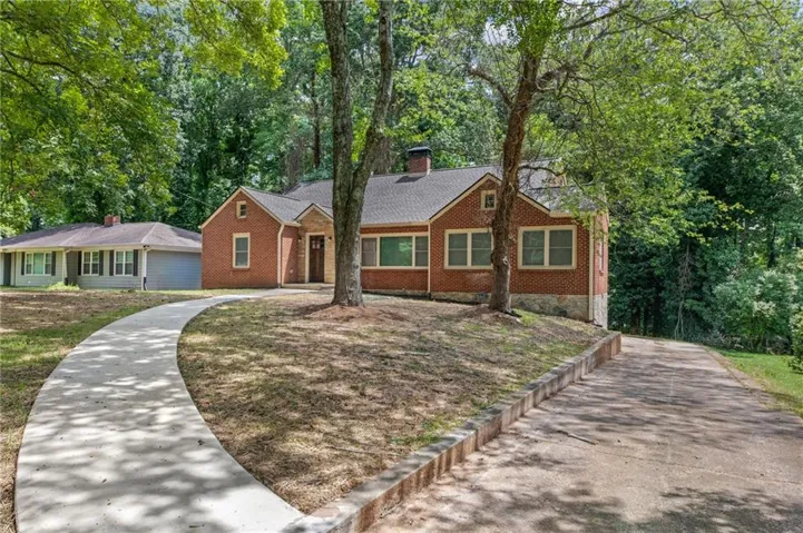 Brick exterior residence with a covered entryway, multiple windows, and a paved driveway