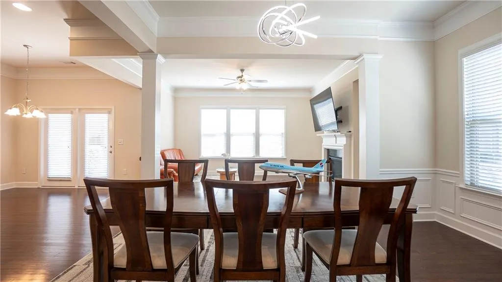 Dining area with suspended lighting, dark wood-type flooring, ceiling fan, ornamental molding, and healthy amount of natural light