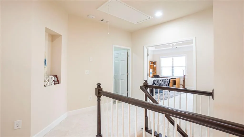 Corridor with an upstairs landing and light carpet