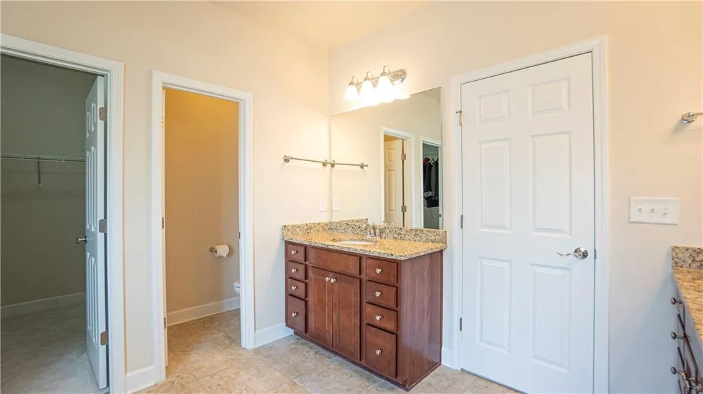 Full bath featuring a spacious closet, vanity, and light tile patterned floors