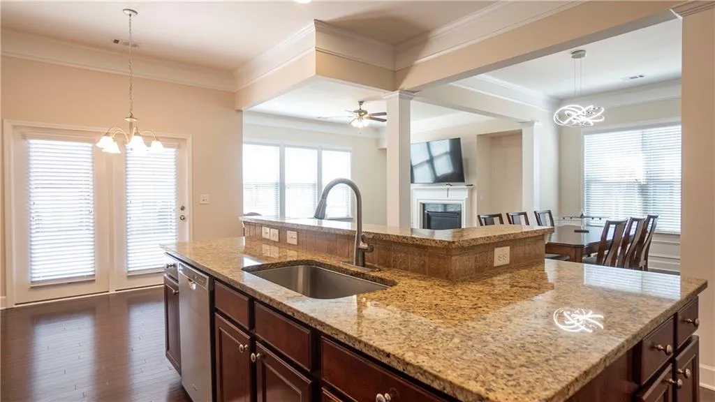 Kitchen featuring hanging lights, light stone counters, a fireplace, ceiling fan, and ornamental molding