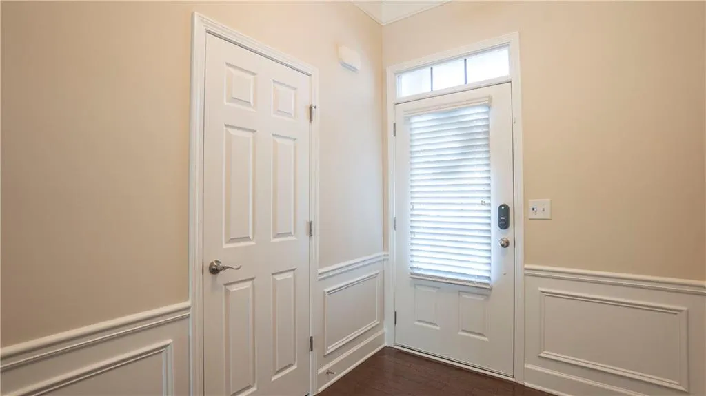Doorway to outside featuring a decorative wall, wainscoting, and wood finished floors