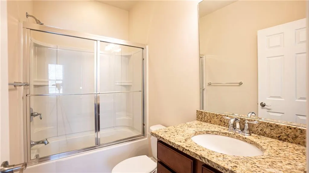 Bathroom featuring vanity and bath / shower combo with glass door