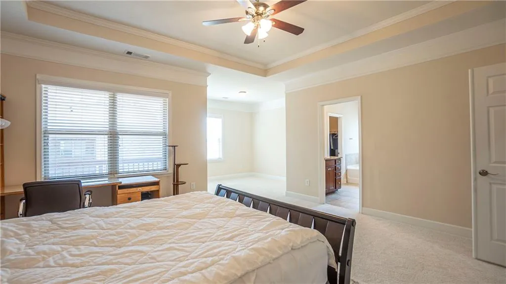 Bedroom with light carpet, ornamental molding, ceiling fan, and ensuite bathroom