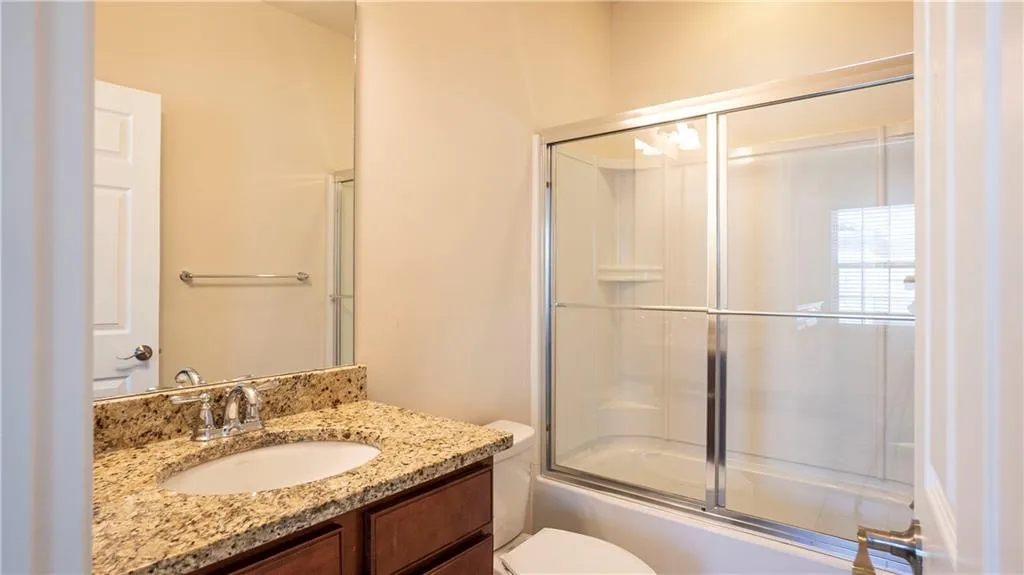 Bathroom featuring vanity and bath / shower combo with glass door