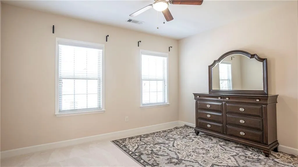 Bedroom with light colored carpet, ceiling fan, and multiple windows