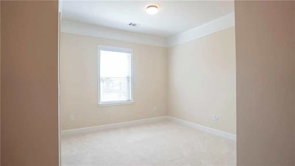 Empty room with ornamental molding and light carpet