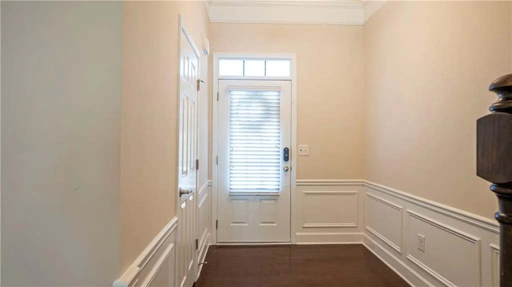 Entryway with a decorative wall, a wainscoted wall, wood finished floors, and ornamental molding