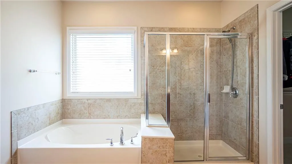 Bathroom with a garden tub, a shower stall, and a spacious closet