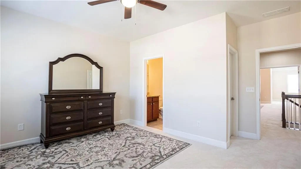 Bedroom featuring light colored carpet, a ceiling fan, and ensuite bath