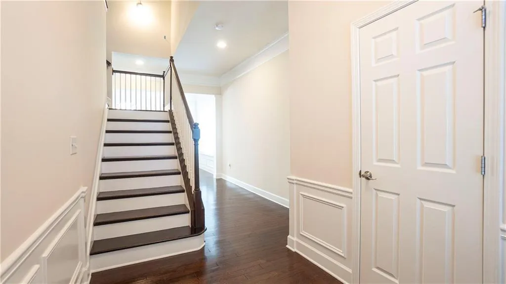 Stairway with hardwood / wood-style floors, wainscoting, crown molding, and a decorative wall