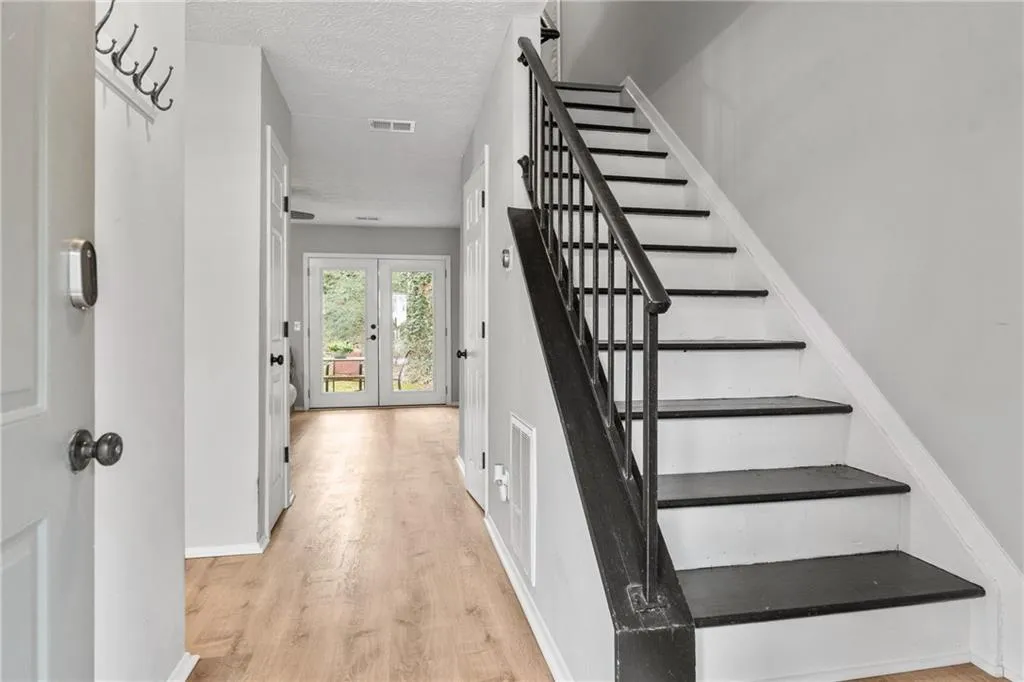 Stairs featuring wood finished floors, a textured ceiling, and french doors