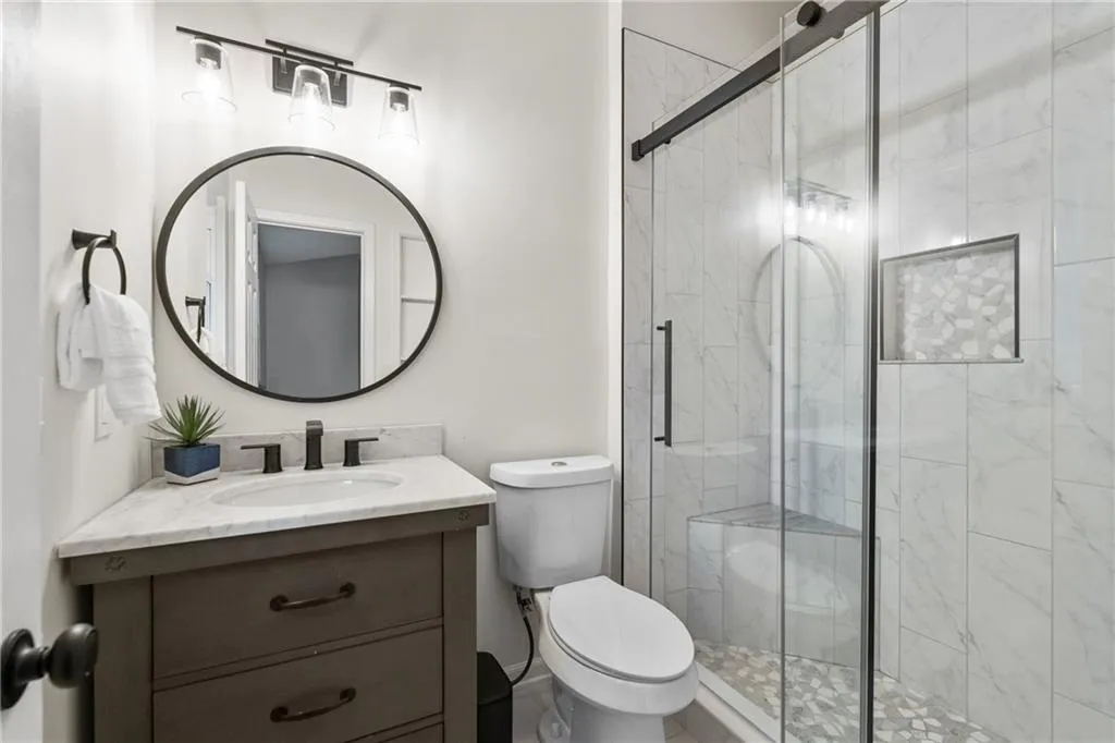 Bathroom featuring a marble finish shower and vanity