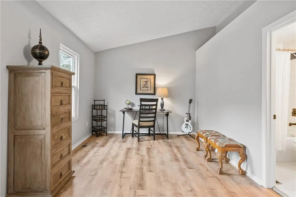 Home office with vaulted ceiling, light wood-style flooring, and a textured ceiling