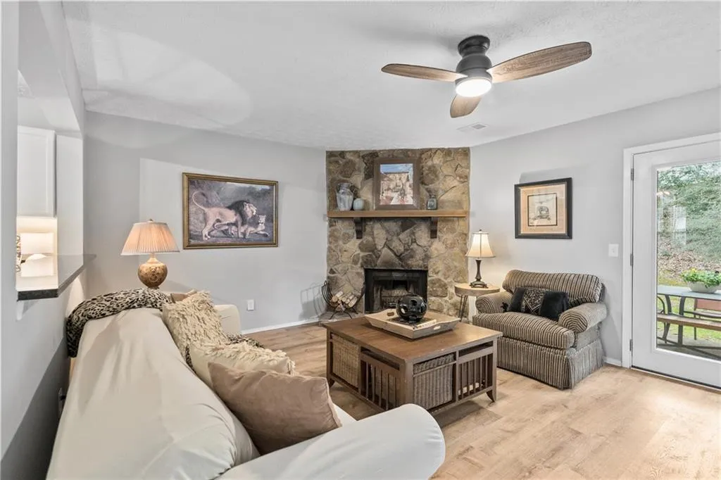 Living room featuring wood finished floors, a fireplace, a ceiling fan, and a textured ceiling