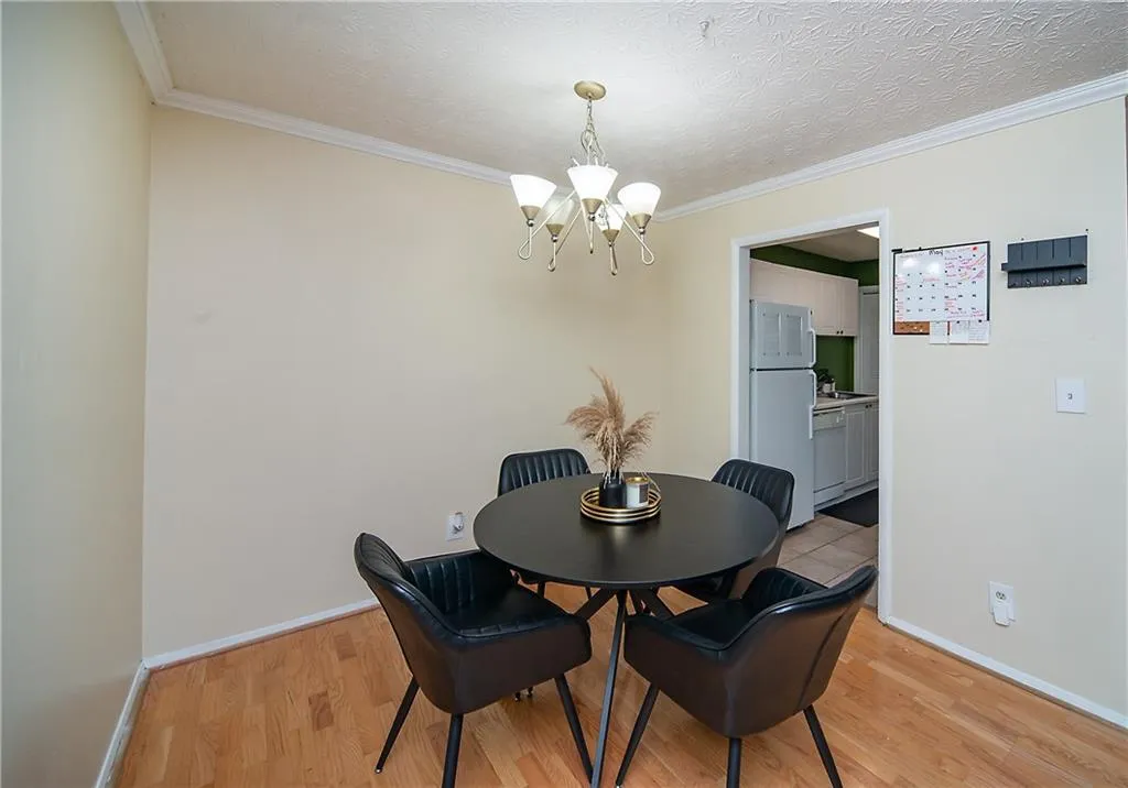 Dining room featuring a chandelier, light wood-style flooring, baseboards, and ornamental molding