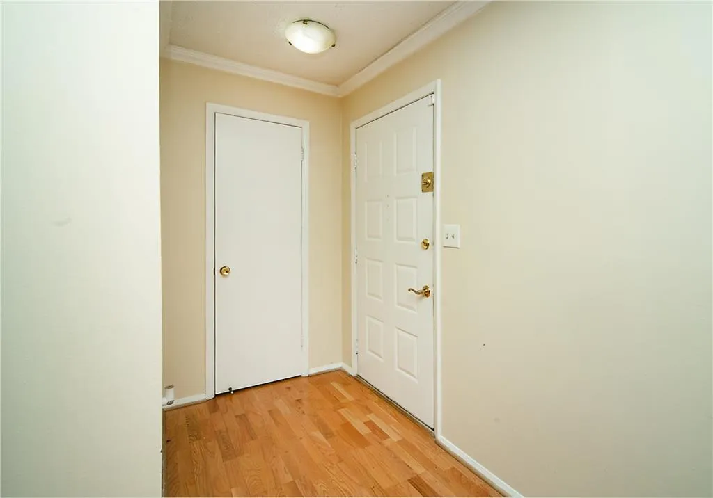 Corridor with crown molding, light wood-style flooring, and baseboards