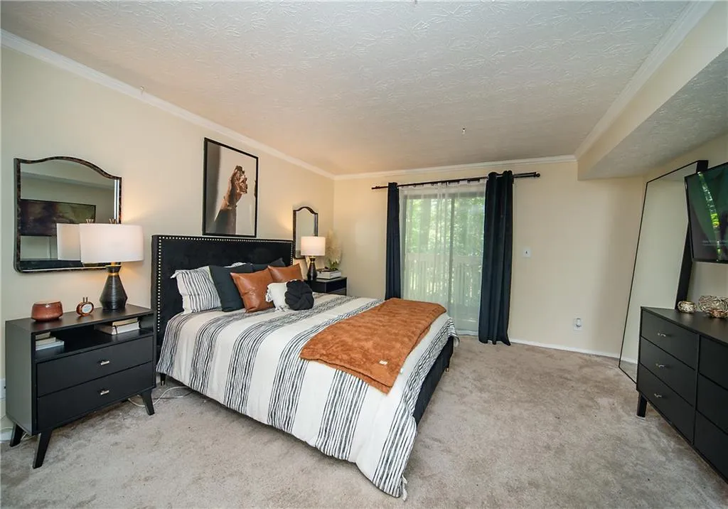 Carpeted bedroom featuring ornamental molding, a textured ceiling, and baseboards