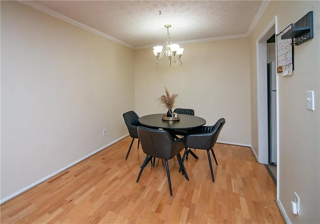 Dining area with a chandelier, light wood-style flooring, ornamental molding, baseboards, and a textured ceiling