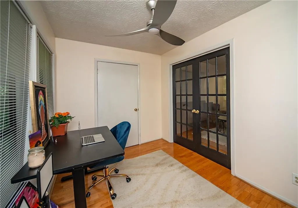 Home office with a ceiling fan, french doors, wood finished floors, and a textured ceiling
