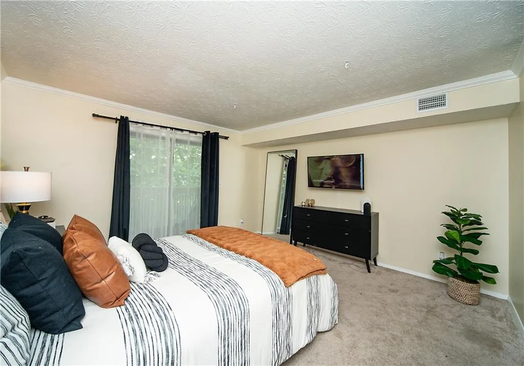 Bedroom with crown molding, a textured ceiling, light colored carpet, and baseboards