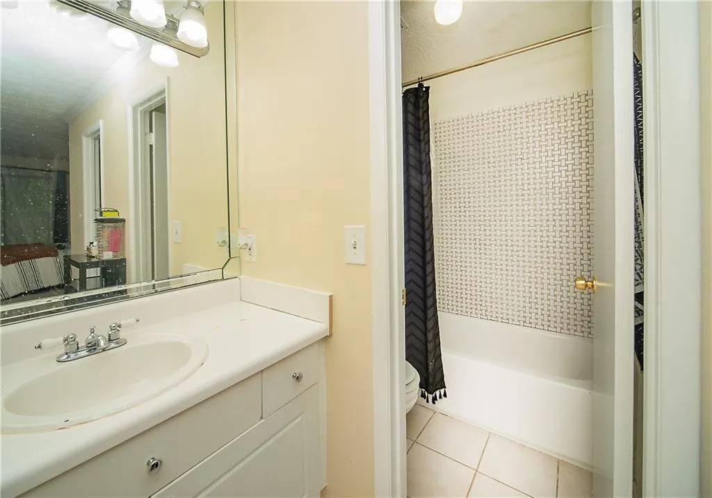 Full bathroom featuring tile patterned floors, toilet, vanity, shower / bath combination with curtain, and crown molding
