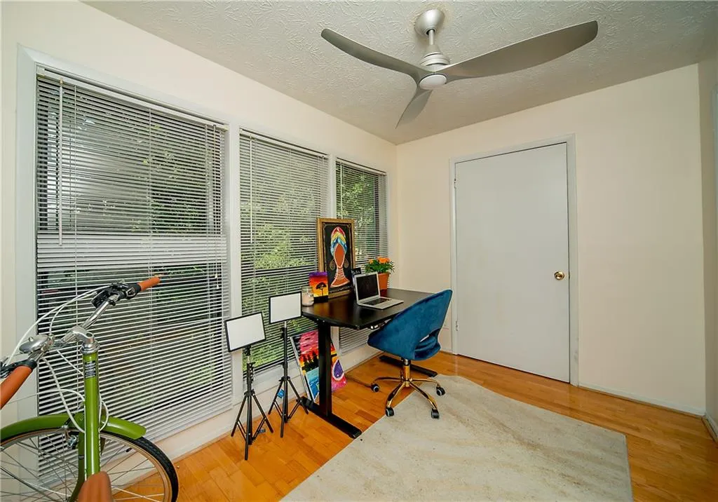 Office space with a ceiling fan, wood finished floors, and a textured ceiling
