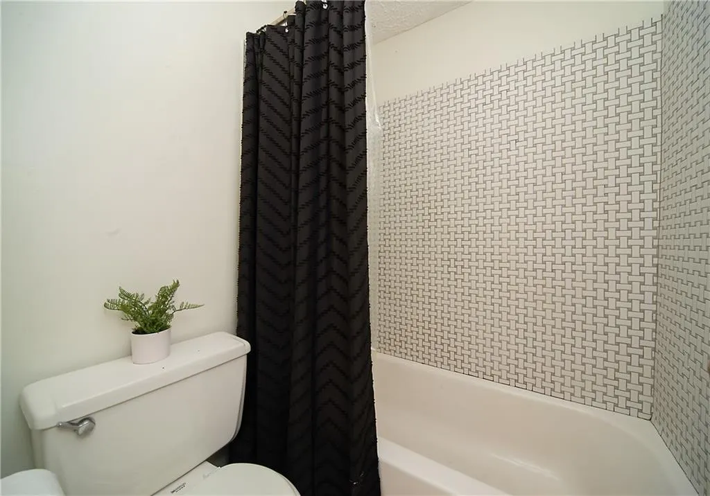 Bathroom featuring toilet and shower / bath combo with shower curtain