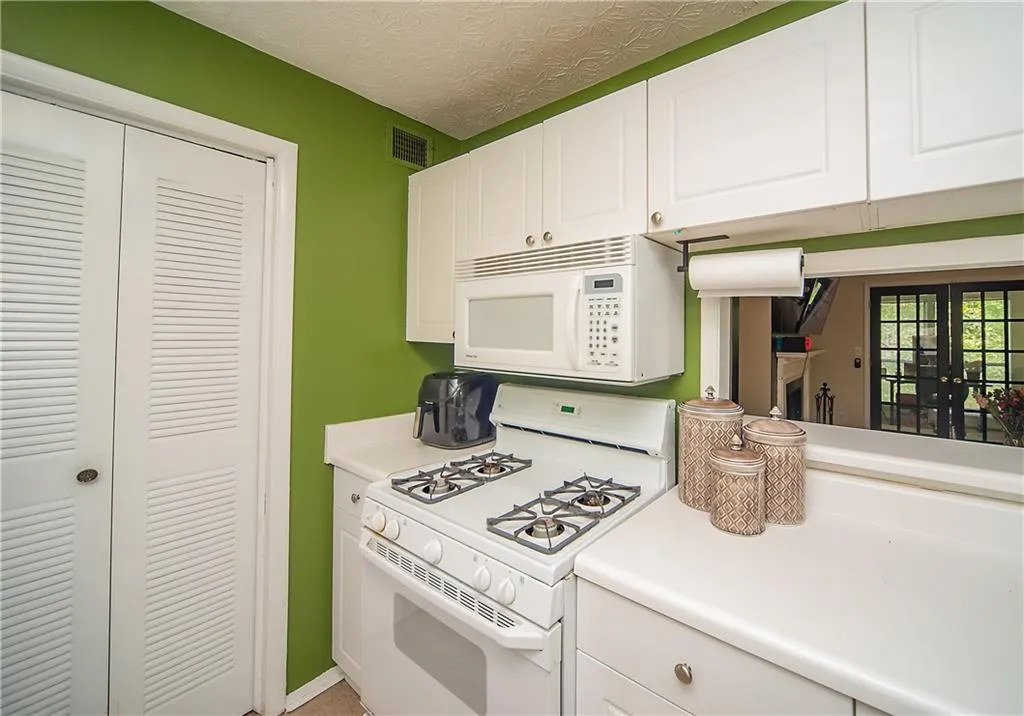 Kitchen with white appliances, white cabinetry, and light countertops