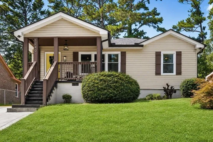 Front exterior with light-colored siding, dark brown shutters, and a covered porch