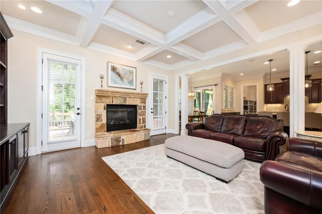 Family Room with a stone fireplace and coffered ceilings. 2 doors leading to back deck.