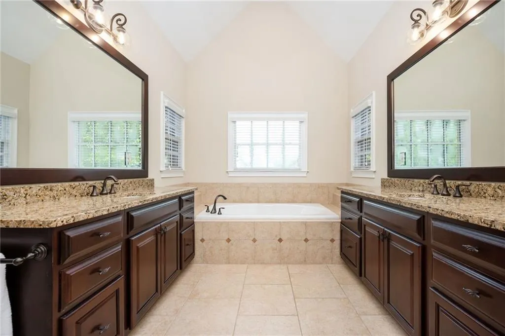 Full bathroom with two separate vanities, jacuzzi tub and separate spacious shower with built in bench.