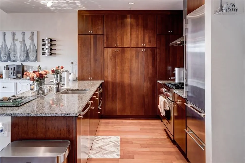 Kitchen featuring sink, light wood-type flooring, high end appliances, and light stone countertops Kitchen featuring sink, light wood-type flooring, high end appliances, and light stone countertops