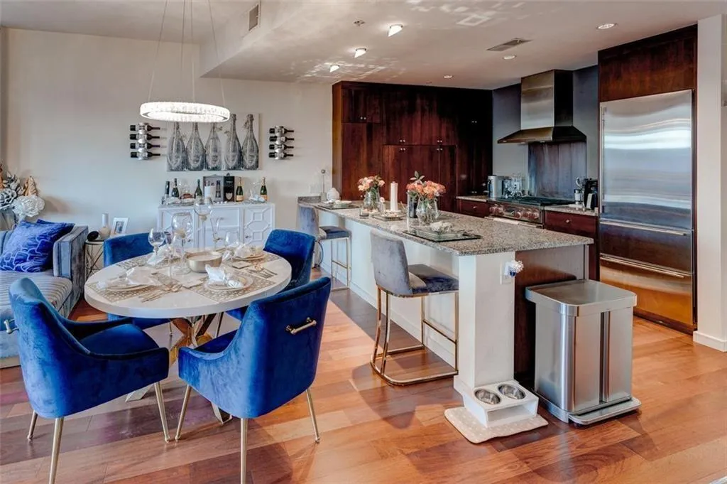 Kitchen featuring wall chimney range hood, light hardwood / wood-style flooring, an island with sink, and stainless steel appliances Kitchen featuring wall chimney range hood, light hardwood / wood-style flooring, an island with sink, and stainless steel appliances