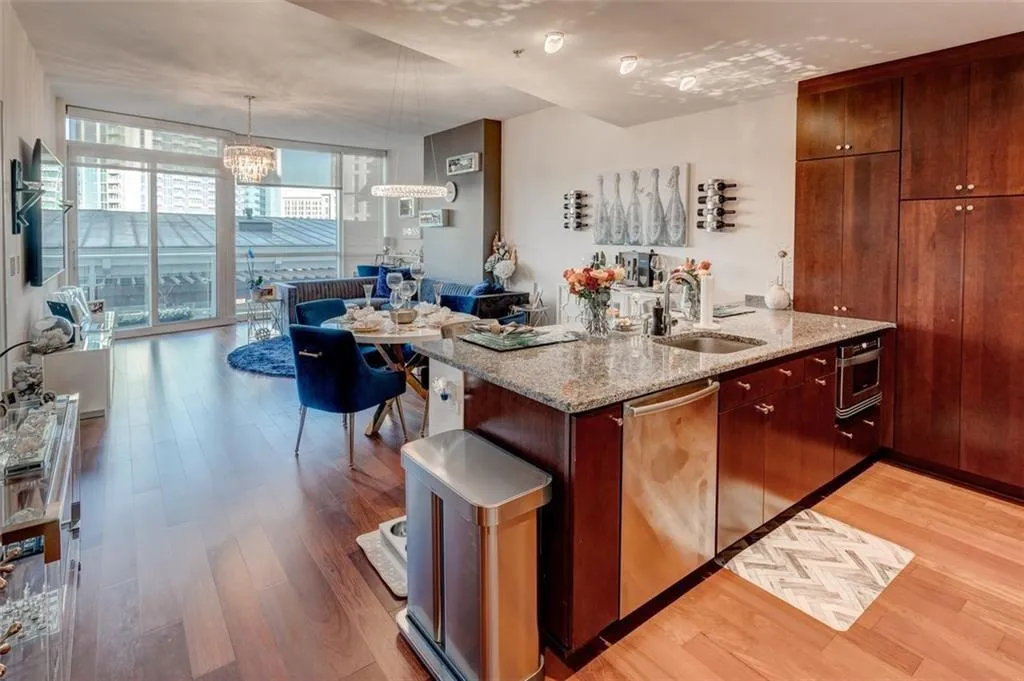 Kitchen with stainless steel dishwasher, sink, expansive windows, and light hardwood / wood-style floors Kitchen with stainless steel dishwasher, sink, expansive windows, and light hardwood / wood-style floors