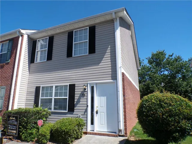 Two-story residential exterior featuring light gray horizontal siding and a red brick lower facade