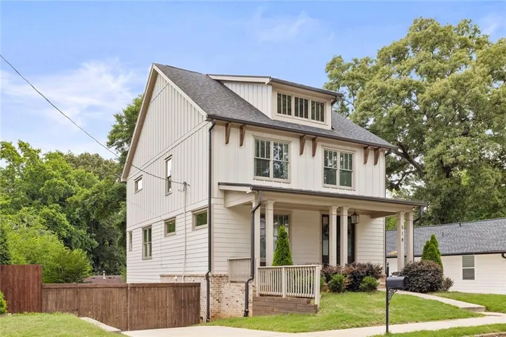Contemporary-style home featuring white board and batten siding, a covered front porch with white columns, dark roof shingles, and a dormer window